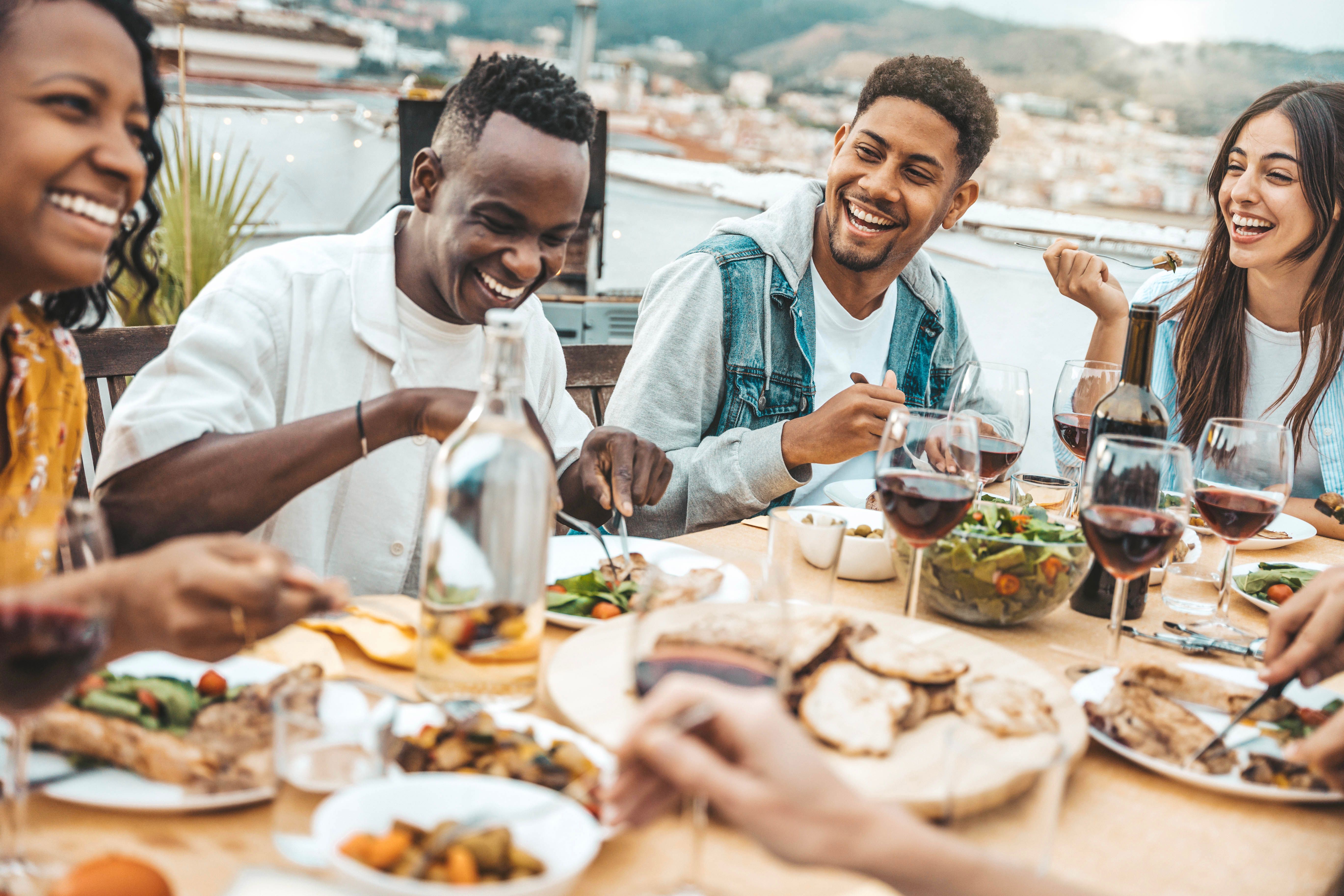 Multiethnic friends having fun at rooftop bbq dinner party