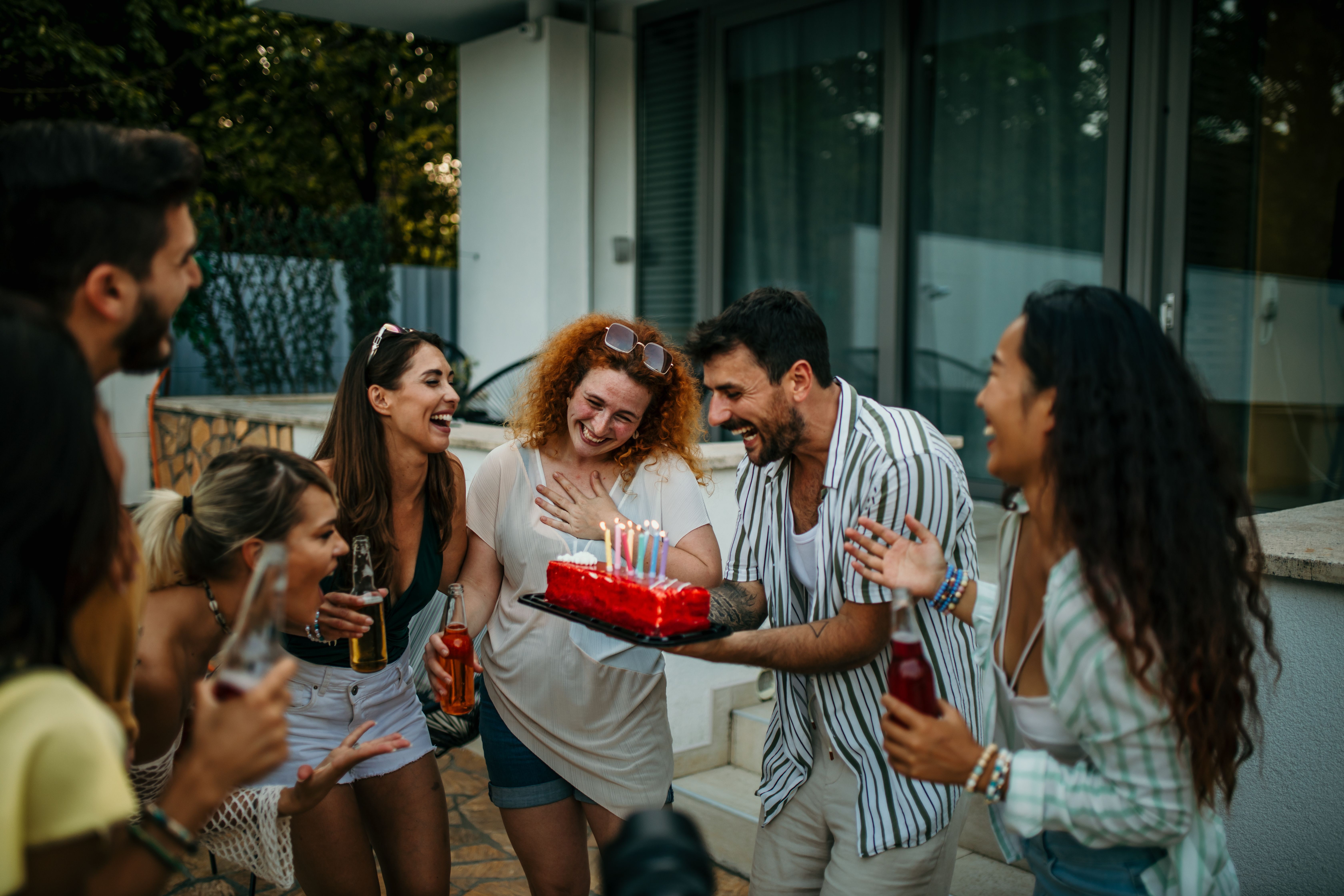 Adults at surprise birthday party with cake