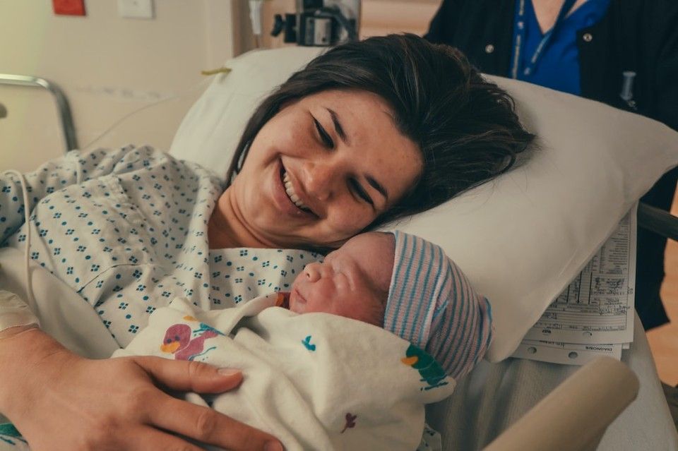 Mom in hospital next to swaddled newborn