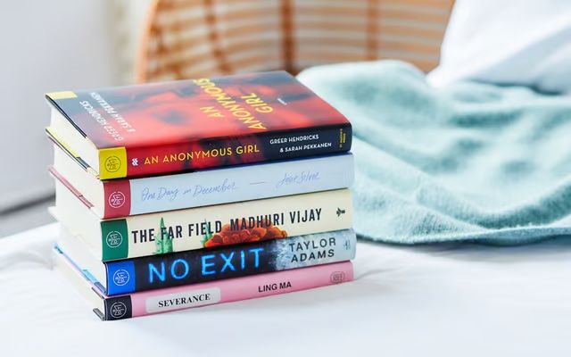 Stack of fiction books on bed