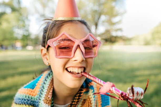 young girl with birthday hat and blower outside