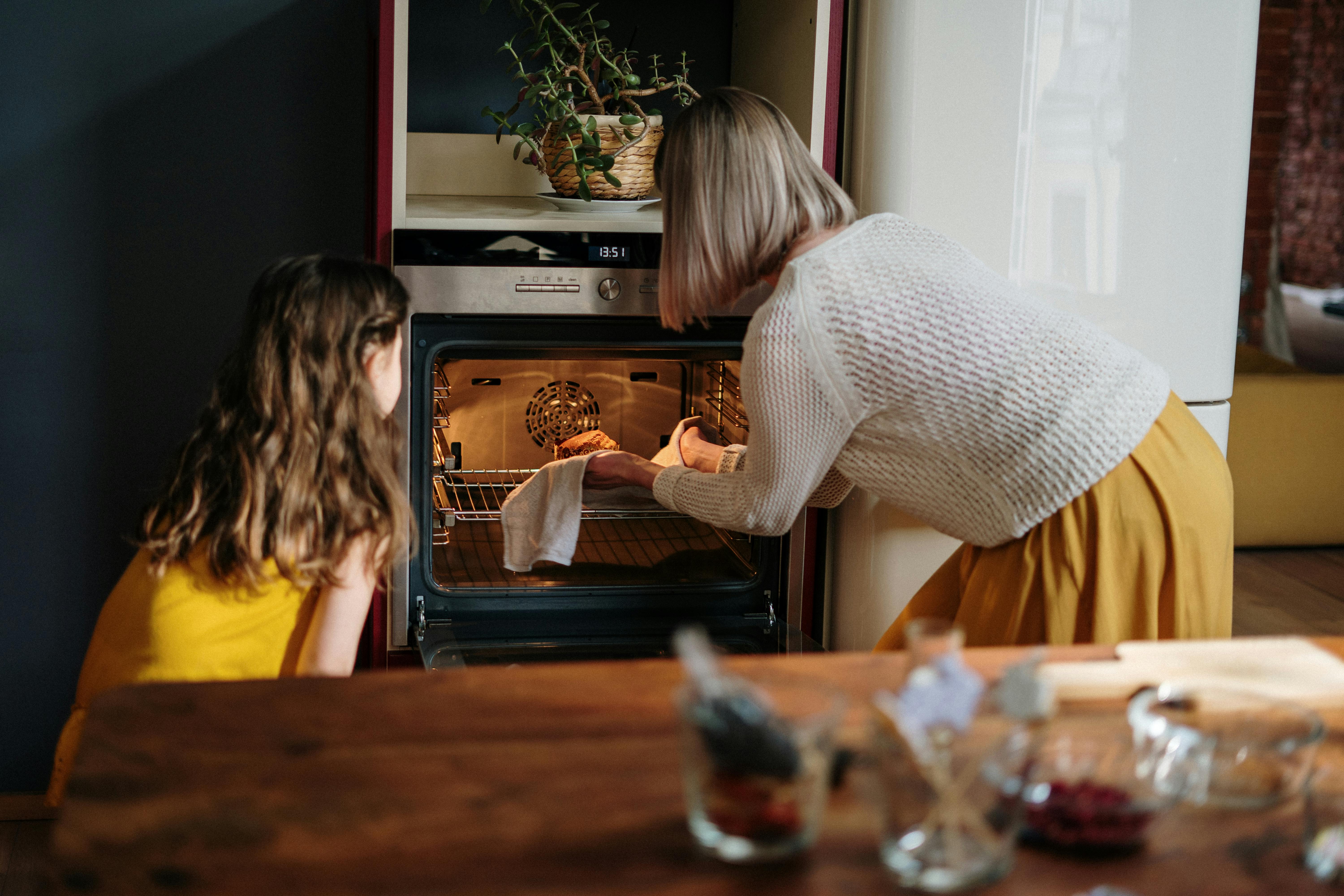 Grandma and grandaughter putting something in the oven